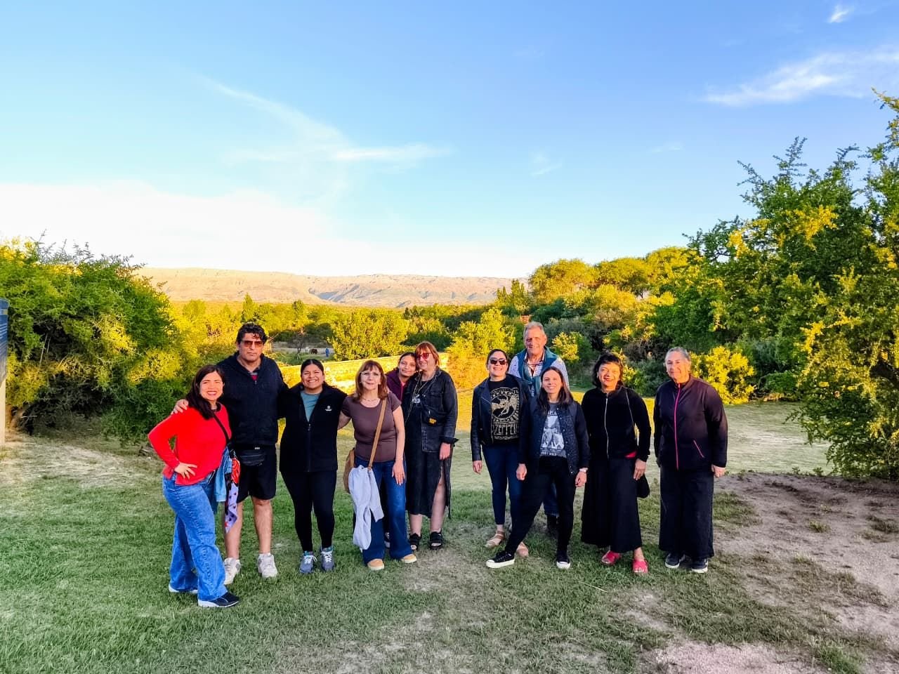 Grupo al atardecer en un parque con sierras de fondo.