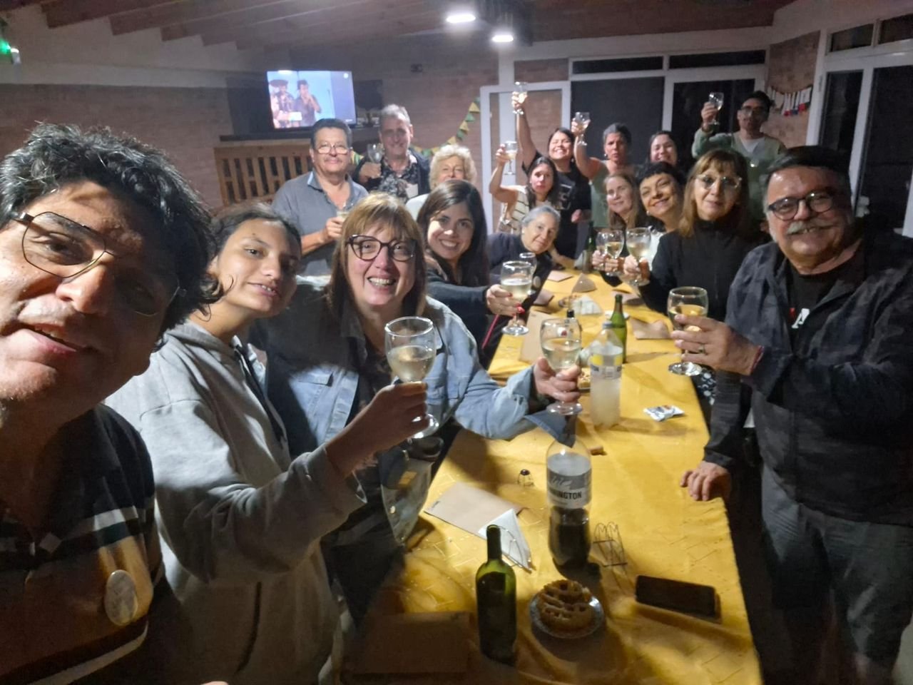 Grupo brindando alrededor de una mesa larga durante una cena.